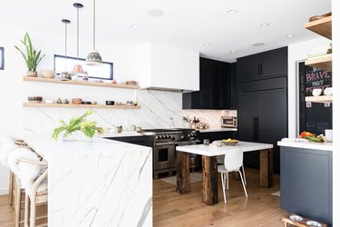 dark kitchen cabinets with light floors and marble backsplash and waterfall countertop
