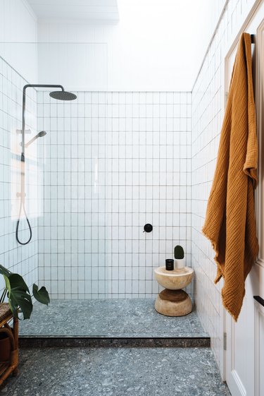 white shower storage ideas with terrazzo floor and wood stool