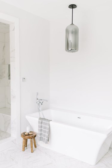 Marble minimalist flooring in white modern bathroom with soaking tub