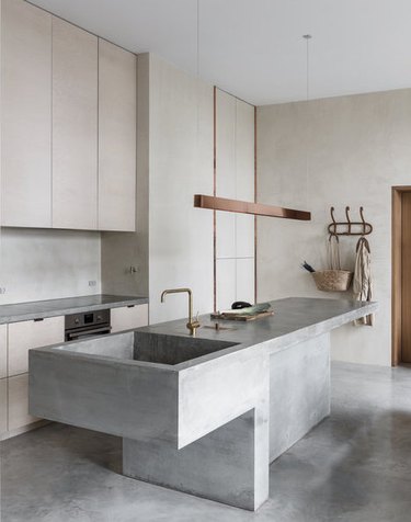 concrete minimalist kitchen sink in kitchen with copper light fixture and concrete floor