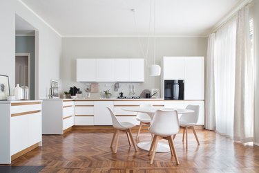 white kitchens with wood floors with scandinavian table and white chairs