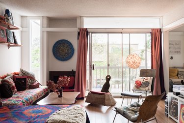 bohemian living room with colorfully patterned couch, orange curtains and balcony
