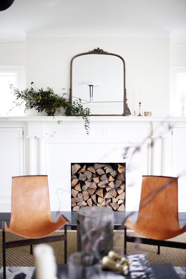 living room mirror ideas with fireplace filled with chopped wood and leather chairs