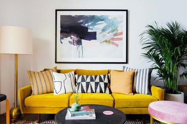 Yellow modern sofa in living room with floor lamp and artwork