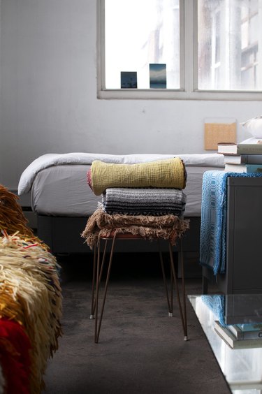 Brooklyn loft with bed and stacked blankets on stool