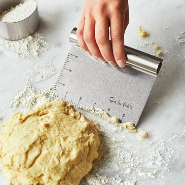 dough with person holding dough scraper nearby