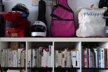 Packed bookshelf with motorcycle helmet and guitar case