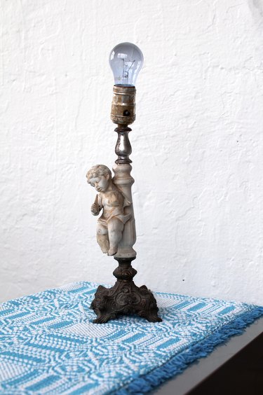 Vintage lamp with cherub atop a turquoise patterned tapestry