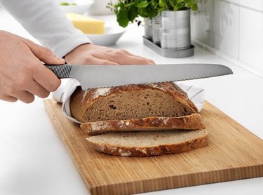 person cutting bread with bread knife