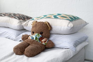 Teddy bear on bed with pillows