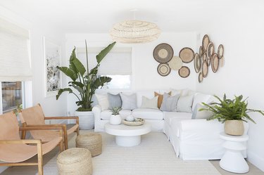 Bohemian living room with white sofa and rattan oversize light fixture.