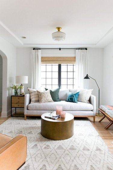 Modern white living room with round coffee table and layered window treatments