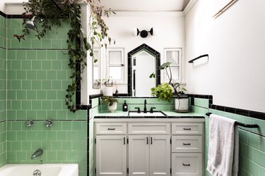 midcentury bathroom with green wall tile and black accents