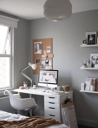 Gray walls with a small white desk in the corner next to a window
