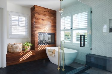 Modern bathroom trend with wood clad fireplace and herringbone tile walls