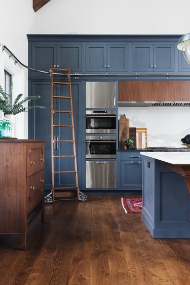 blue tall kitchen cabinets with library ladder