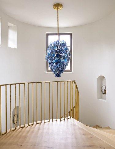 blue chandelier over gold modern stair railing