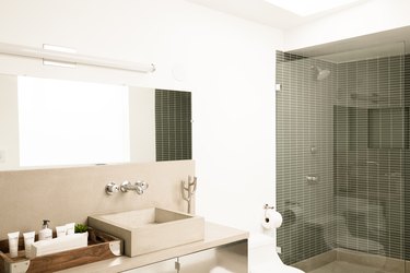 neutral-colored bathroom with shower with glass door, stone bathroom vanity cabinet and sink