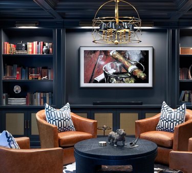 basement lighting in dark gray basement with built in book cases and gold chandelier