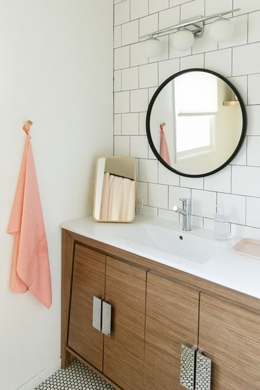 single-sink vanity, circular mirror and large, subway tile backsplash