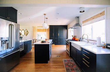 navy tall kitchen cabinets with brass hardware and white countertops