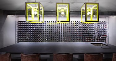 basement lighting in basement with dark gray bar and wine cellar, lime green pendant lights.