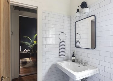 bathroom pedestal sink, rectangular mirror, decorative lights and subway tile wall tile