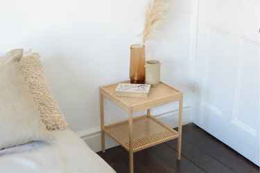 End table with cane detailing, vases, pillows.