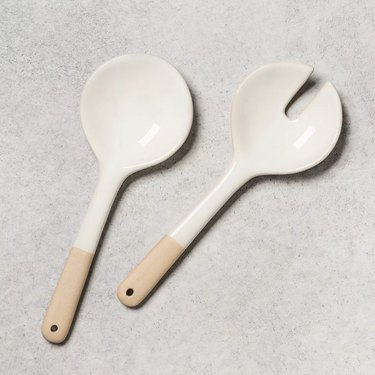 two salad tongs with white top and wood handle