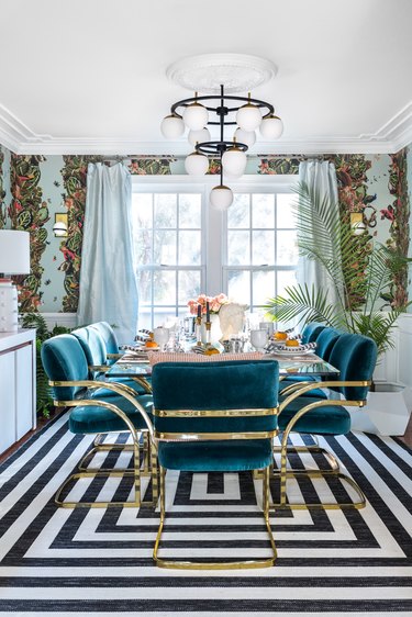 Black and turquoise art deco dining room with velvet and brass chairs and globe-style light fixture