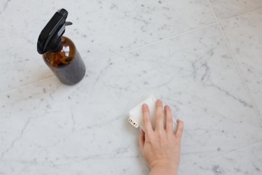 Hand using sponge to clean marble counter