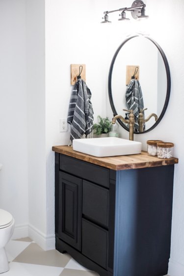 Dark minimalist bathroom vanity with circular mirror.