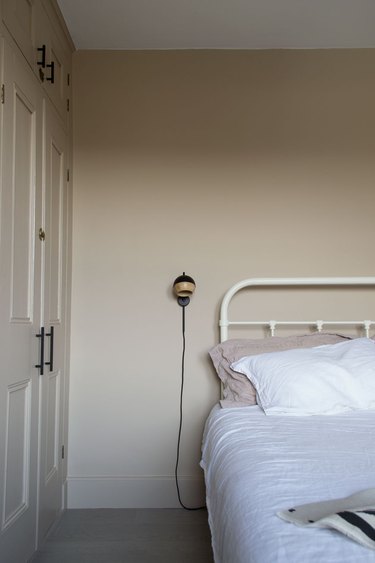 taupe minimalist bedroom idea with wall light