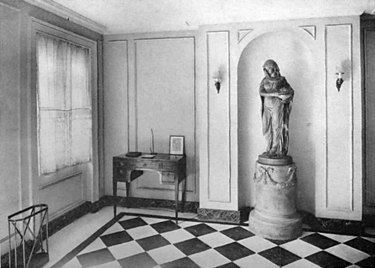 black and white photograph of space with large statue and checkered floor