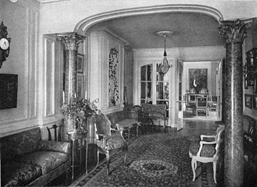 black and white photograph of interior with seating, patterned rug, and chandelier