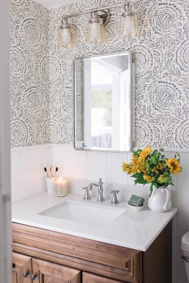 small farmhouse bathroom idea with statement wallpaper and farmhouse lighting