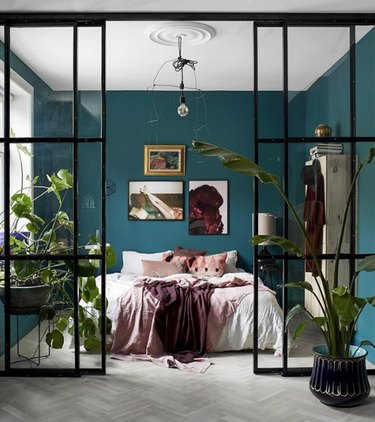 bohemian teal bedroom with white ceiling and factory style doors