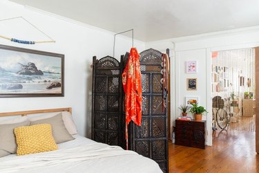 eclectic bedroom with ornate room divider screen and midcentury art