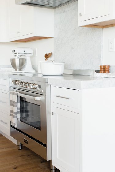 stainless steel oven and white cabinetry with white stone countertops