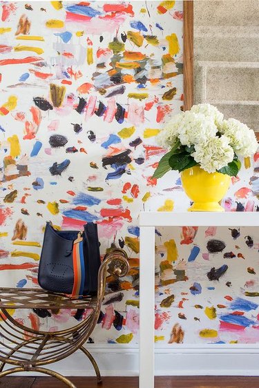 abstract modern wallpaper in entryway with yellow vase and flowers
