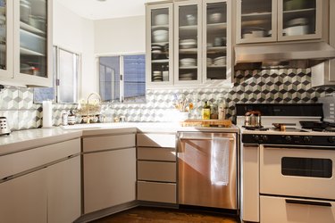 view of kitchen with cabinets with glass inserts, corner sink and stove