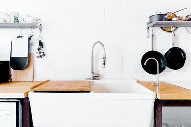 large kitchen sink, chrome faucet and hanging cast iron pans