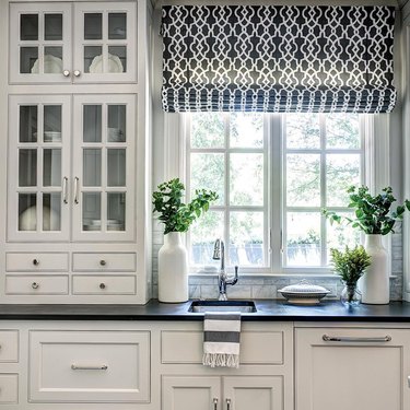 Black and white farmhouse kitchen with white cabinets and slate countertops