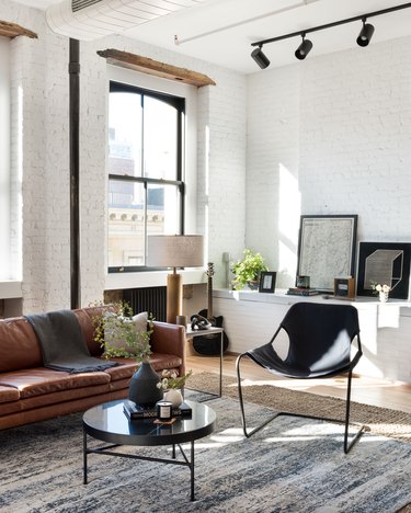 white industrial living room idea with exposed brick brown leather sofa