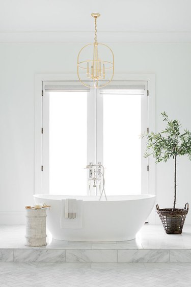 white bathroom idea with freestanding tub on raised platform and French doors