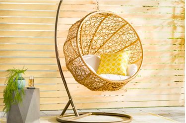 Hanging birdnest chair on stand side table with plant