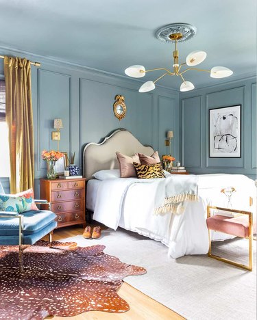 traditional bedroom with blue walls and ceiling and layered rugs and floor to ceiling drapery