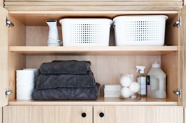 cabinet storage with storage baskets, cleaning supplies and towels