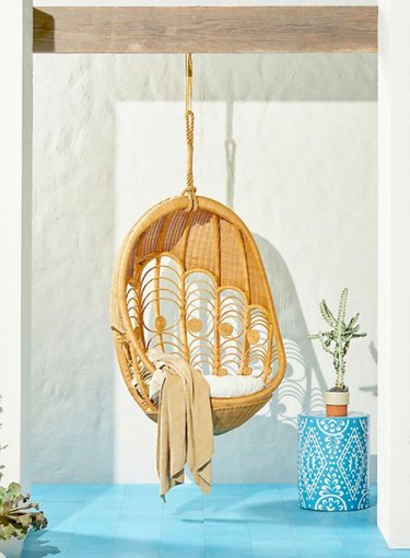 hanging peacock patterened wicker chair blue floor tile side table