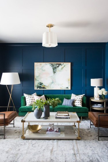 living room with navy blue walls and emerald green sofa